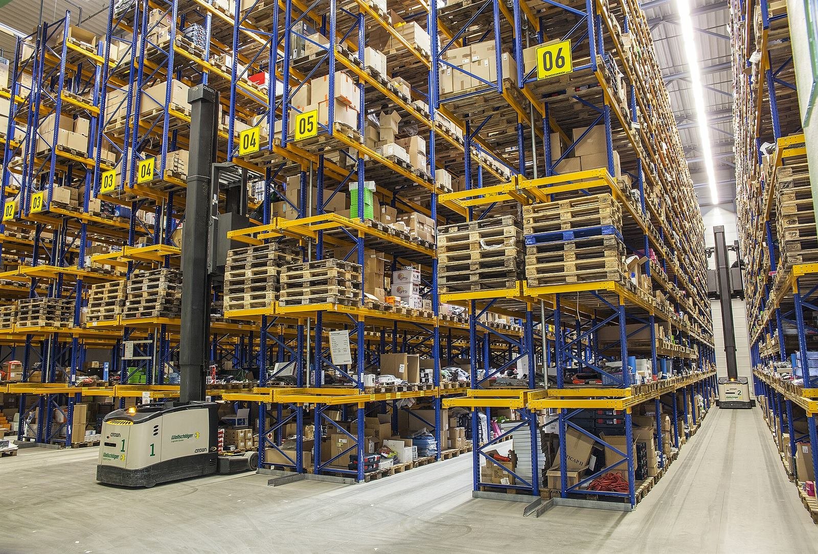 High-bay warehouse aisle with numbered pallet racking and order picker